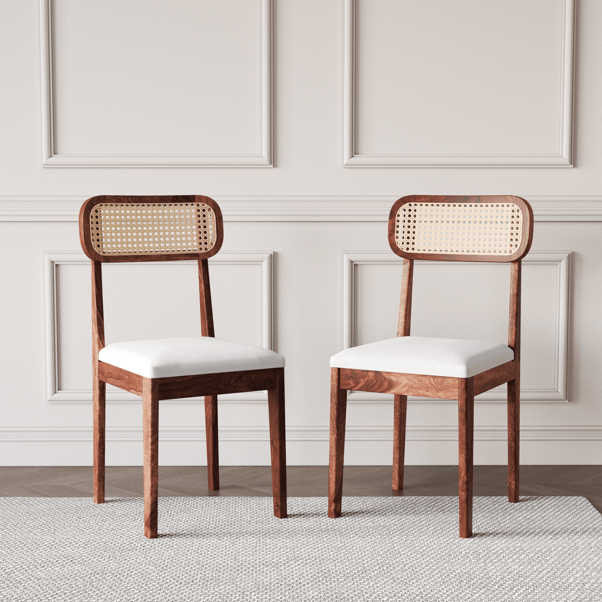 Two wooden chairs with wicker backrests and white cushions on a neutral background