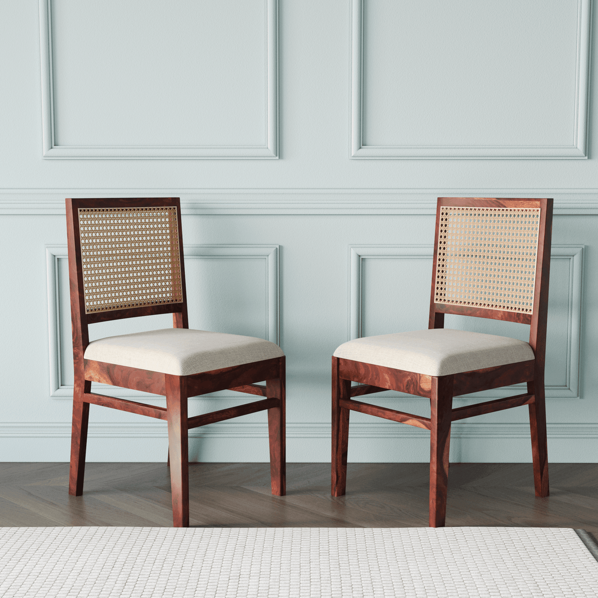 Two wooden chairs with wicker backrests and white cushions 
