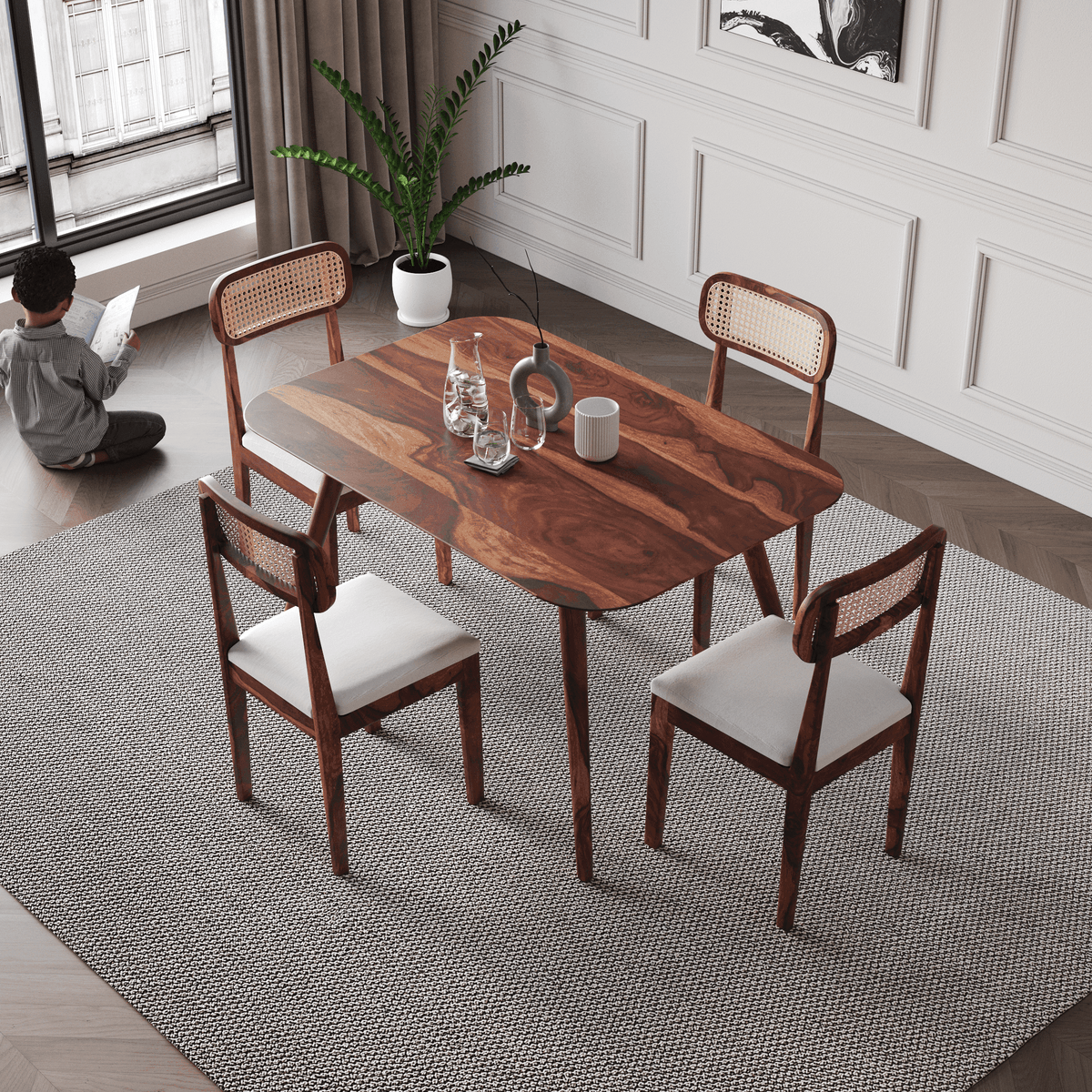 Dining table set with chairs in a room with a child reading by a window.