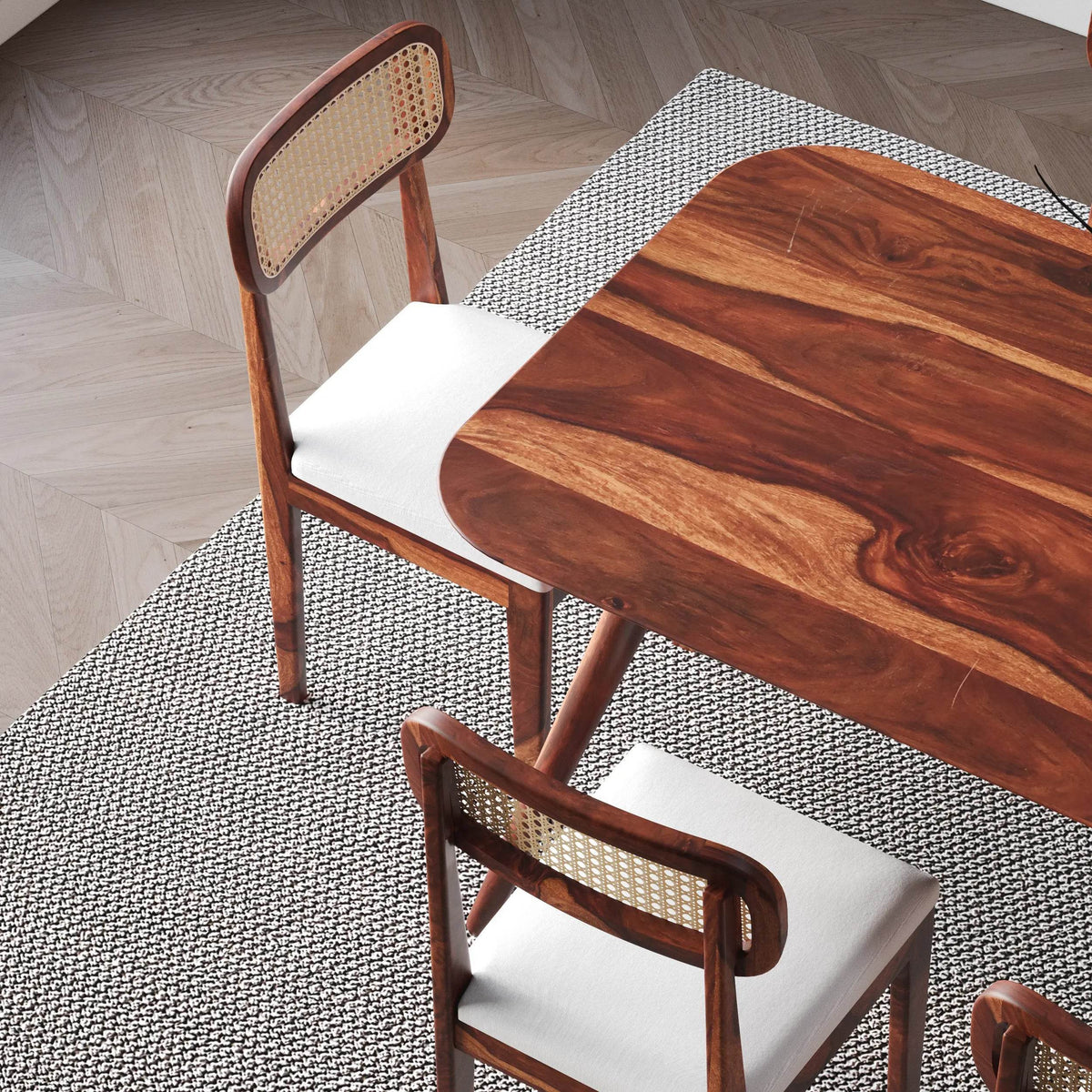 Wooden table and chairs with woven backrests on a textured floor.