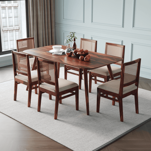 Wooden dining table with six chairs in a room with white walls and a window.