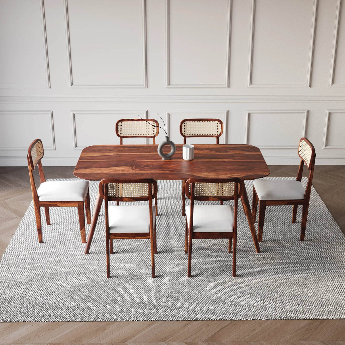 Dining table set with chairs in a room with panelled walls and wooden floor.