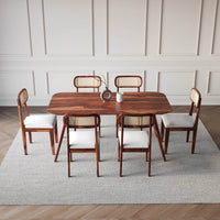 Dining table set with chairs in a room with panelled walls and wooden floor.