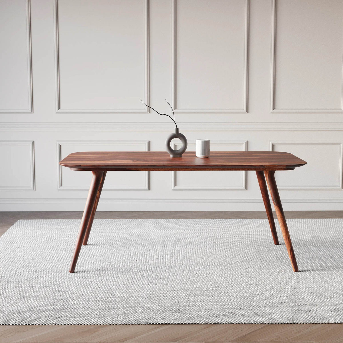 Wooden dining table with decorative items in a minimalistic room.