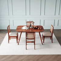 Wooden dining table with four chairs in a room with light blue paneled walls.