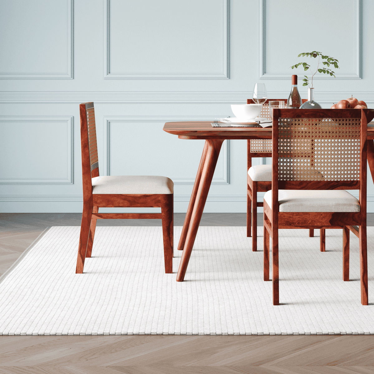 Dining table with wooden chairs in a room with light blue walls and a white rug.