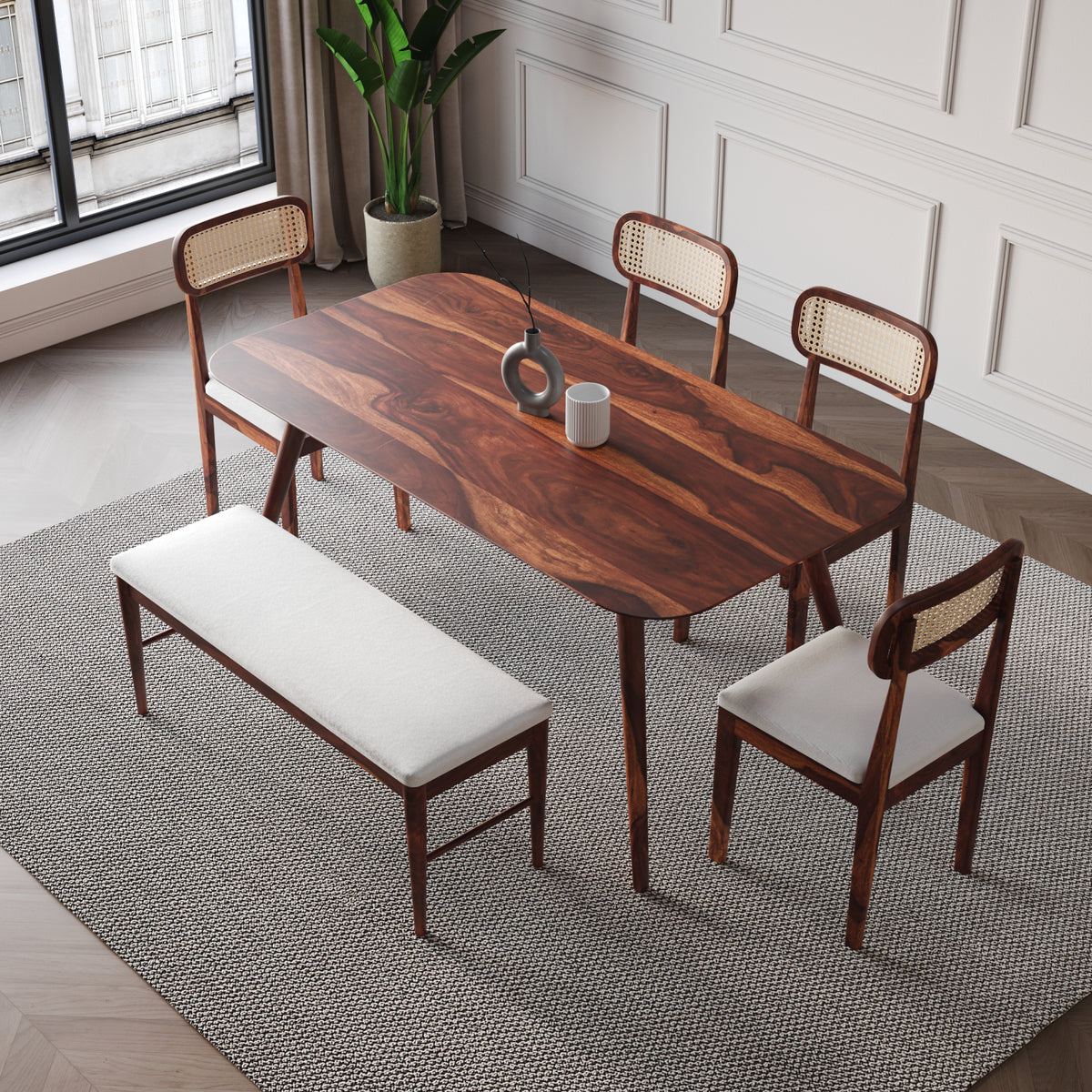 Dining room set with wooden table, chairs, and bench on a patterned rug.