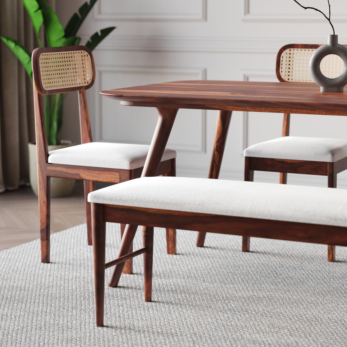 Dining room with wooden table, chairs, and bench on a light gray rug.