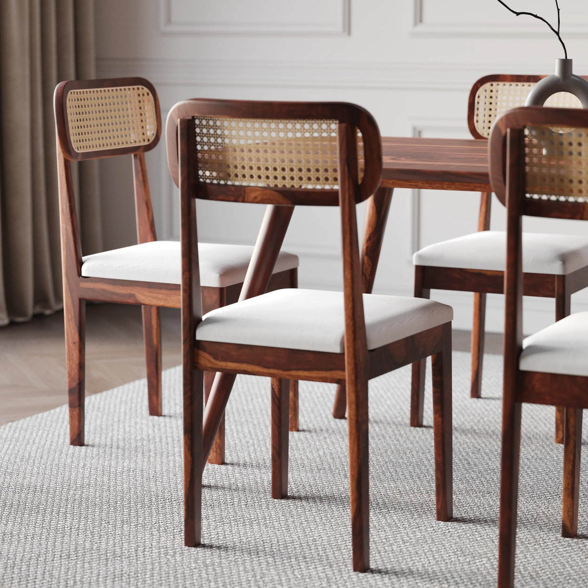 Dining room with wooden chairs with wicker backrests and white cushions.