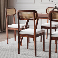Dining room with wooden chairs with wicker backrests and white cushions.