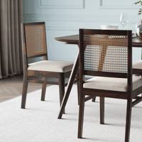 Dining table with two chairs featuring woven backrests and beige cushions in a room with chair view