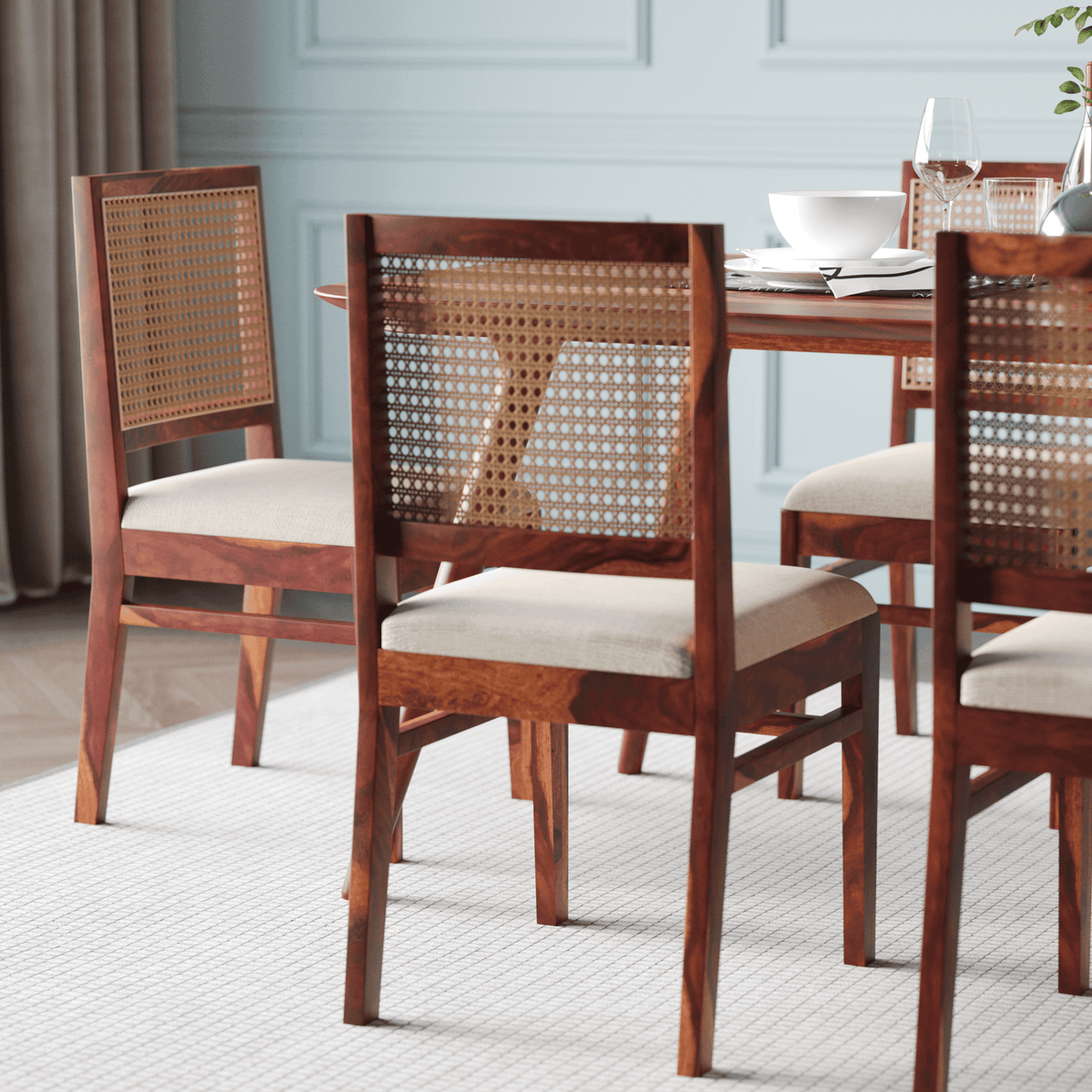 Wooden dining chairs with wicker backrests in a room with light blue walls.