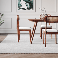 Dining room with wooden table and chairs on a light gray rug.