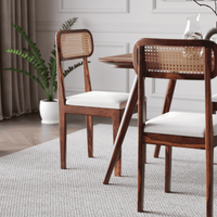 Wooden chairs with wicker backrests in a dining room setting.