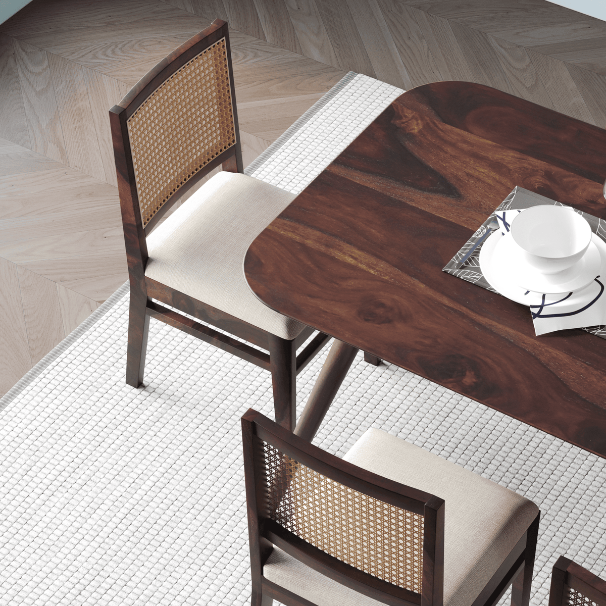 Wooden dining table with two chairs in a room with wooden flooring.