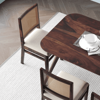 Wooden dining table with two chairs in a room with wooden flooring.