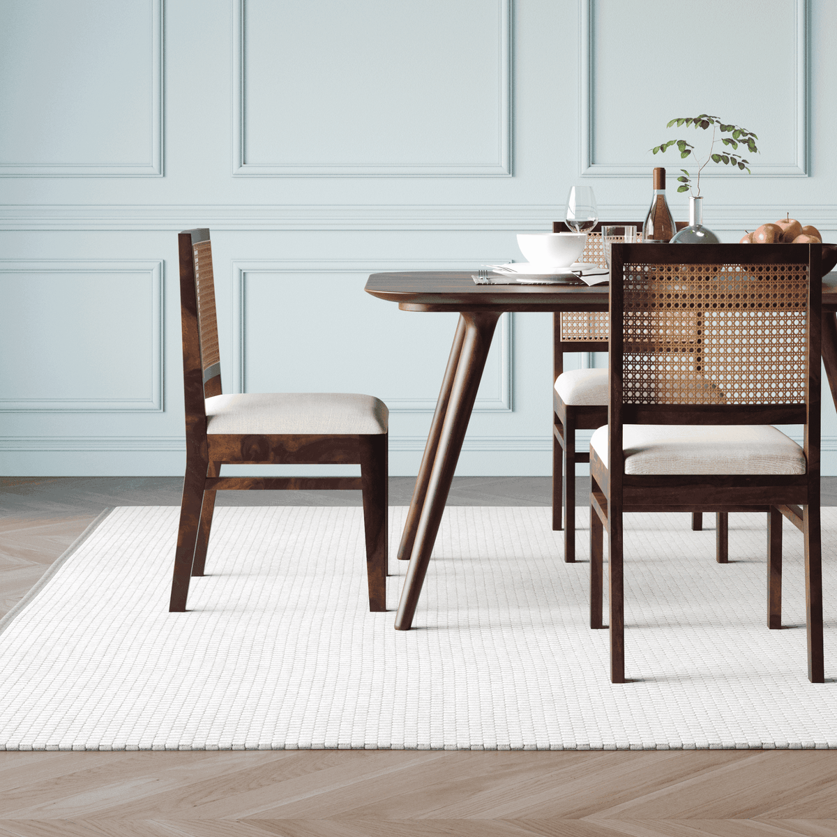 Dining table with chairs in a room with light blue walls and wooden flooring.