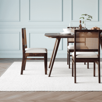 Dining table with chairs in a room with light blue walls and wooden flooring.