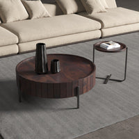 Round wooden coffee table with decorative items in a living room setting.