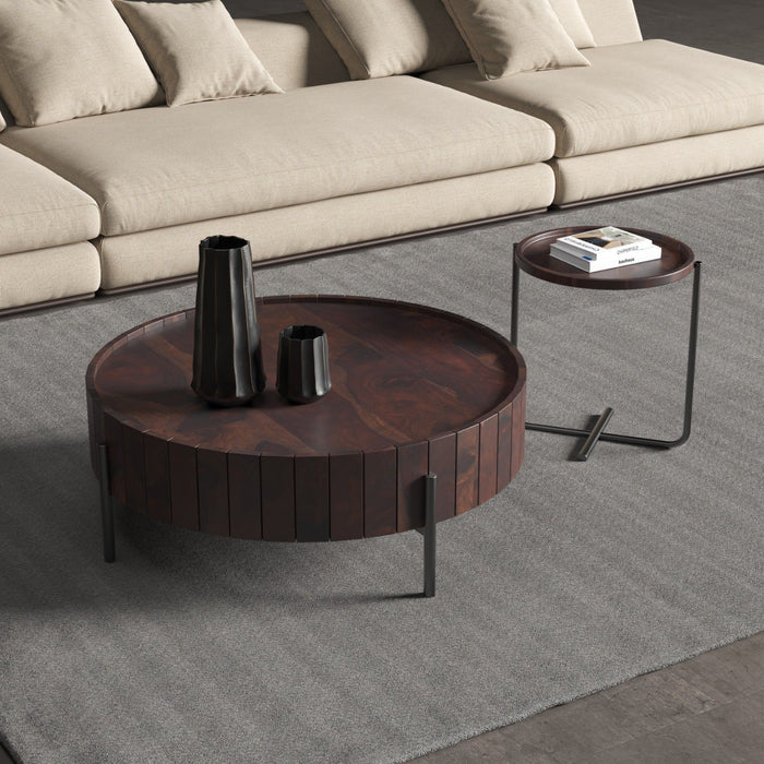 Round wooden coffee table with decorative items in a living room setting.