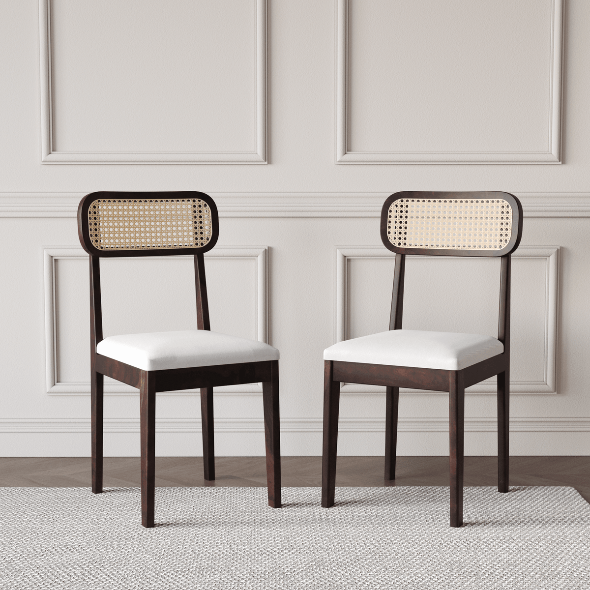 Two wooden chairs with wicker backrests and white cushions on a neutral background